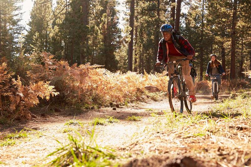 Black man and Caucasian woman riding bikes on a forest trail, stock photo