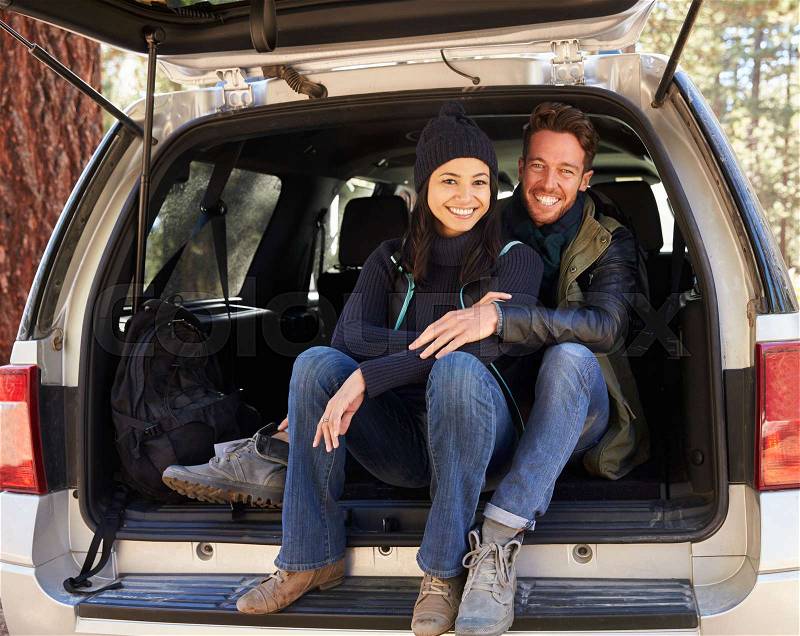 Portrait of couple sitting in open back of car before hiking, stock photo