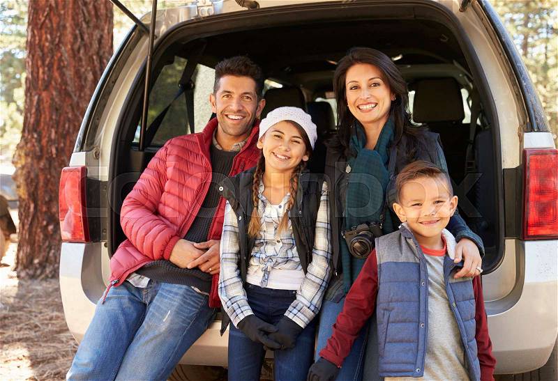 Portrait of family sitting in open back of car before a hike, stock photo
