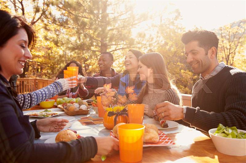 Group of happy friends eat and drink at a table at a barbecue, stock photo