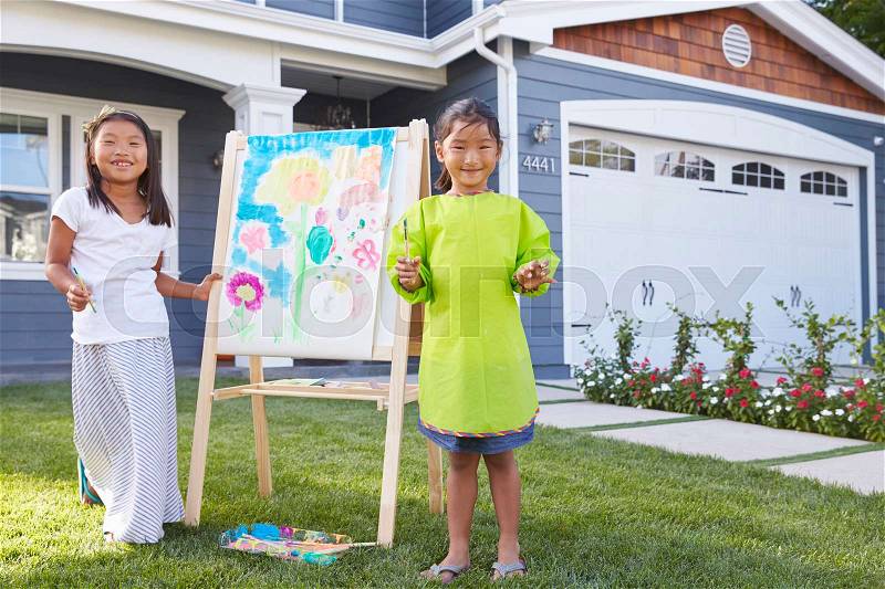 Portrait Of Two Girls Painting Picture In Garden, stock photo