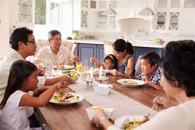 Extended Family Group Eating Meal At Home Together, stock photo