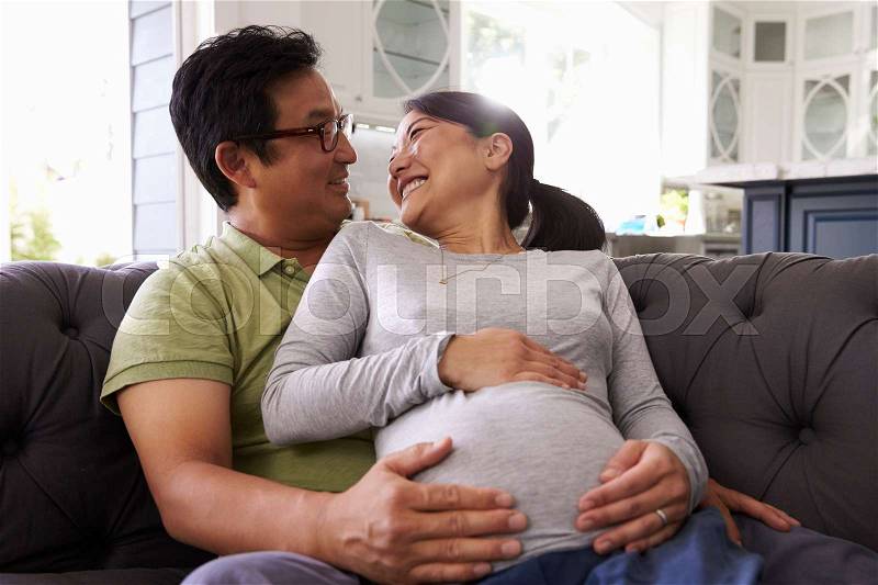 Expectant Couple Relaxing On Sofa At Home Together, stock photo
