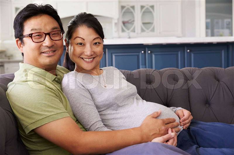 Expectant Couple Relaxing On Sofa At Home Together, stock photo