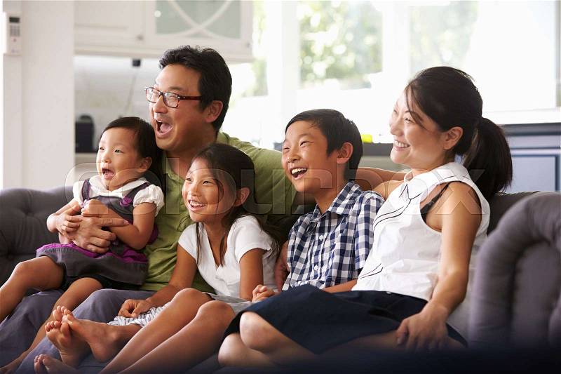 Family Sitting On Sofa At Home Watching TV Together, stock photo