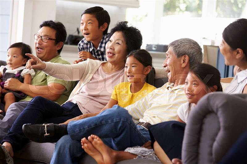 Extended Family Group At Home Watching TV Together, stock photo