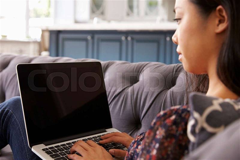 Woman Relaxing On Sofa At Home Using Laptop, stock photo