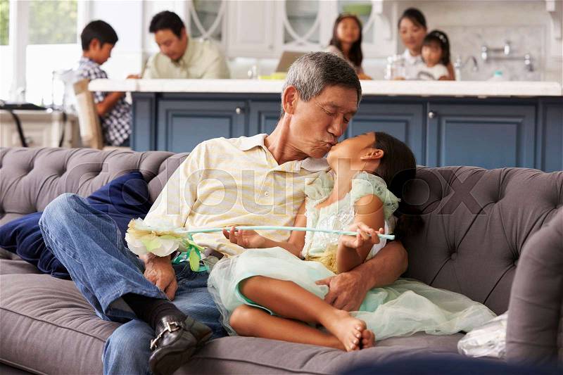 Grandfather And Granddaughter Relaxing On Sofa At Home, stock photo