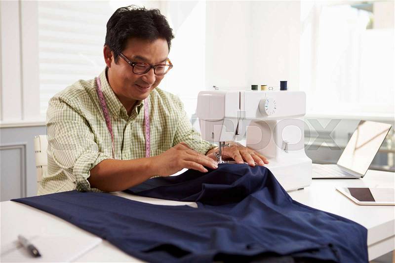 Man Making Clothes Using Sewing Machine At Home, stock photo