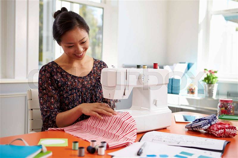 Woman Making Clothes Using Sewing Machine At Home, stock photo