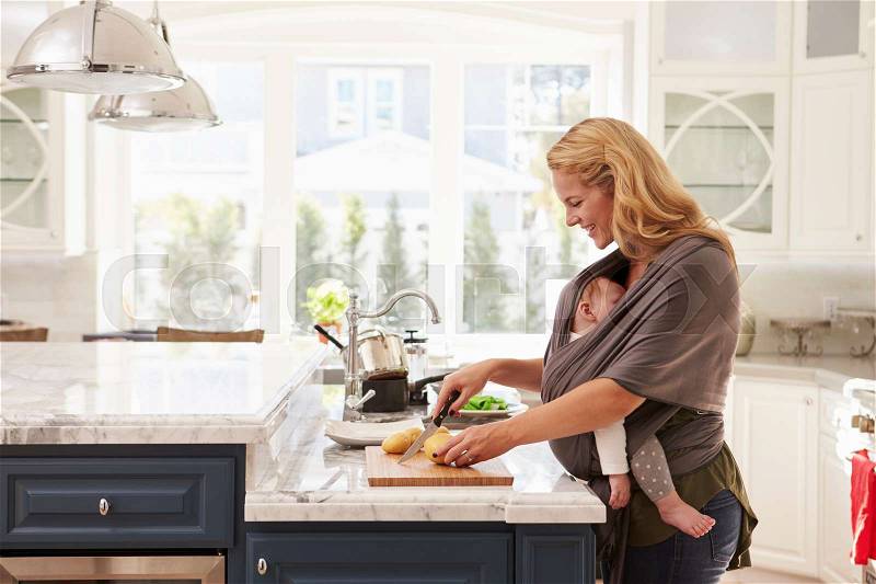 Busy Mother With Baby In Sling Multitasking At Home, stock photo
