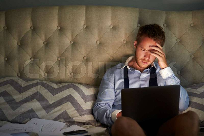 Businessman At Home On Bed Working Late On Laptop, stock photo