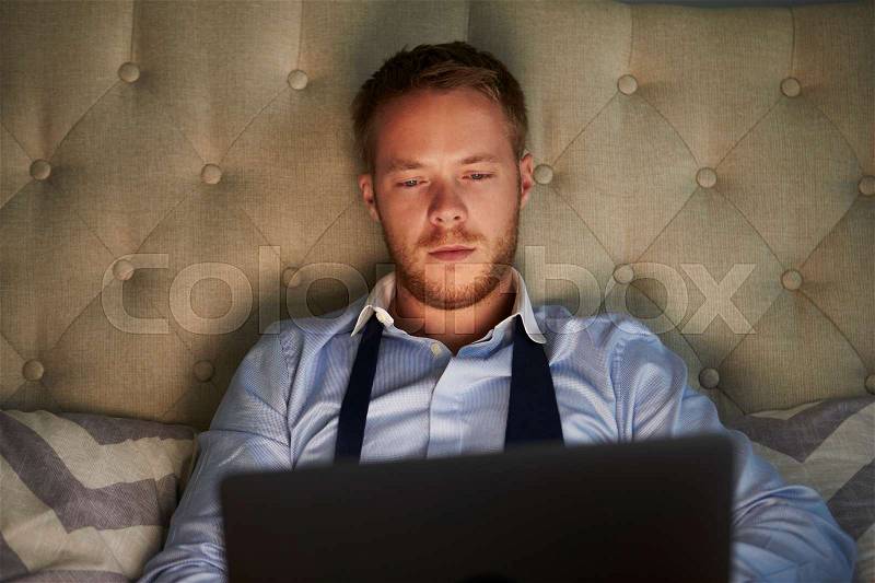 Businessman At Home On Bed Working Late On Laptop, stock photo