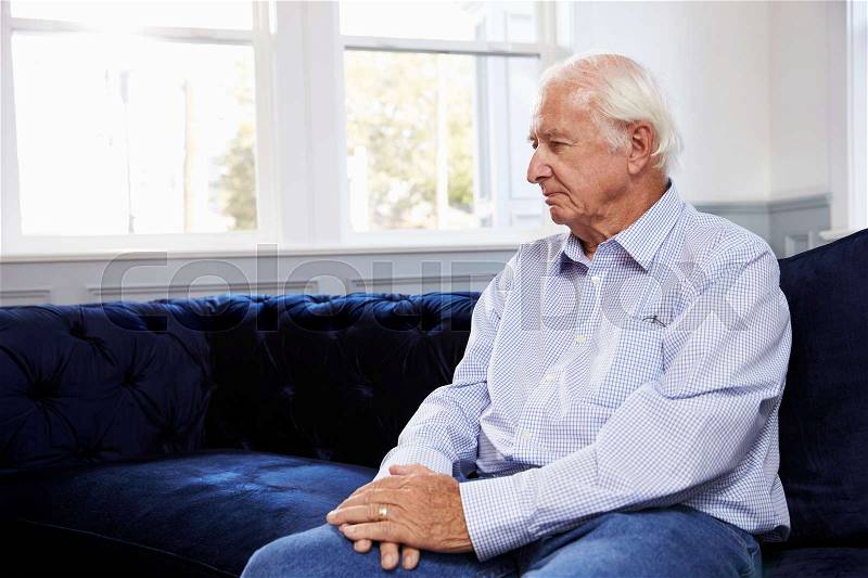 Depressed Senior Man Sitting On Sofa At Home, stock photo