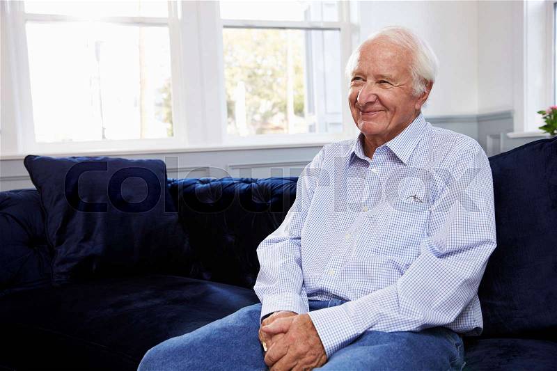 Smiling Senior Man Sitting On Sofa At Home, stock photo