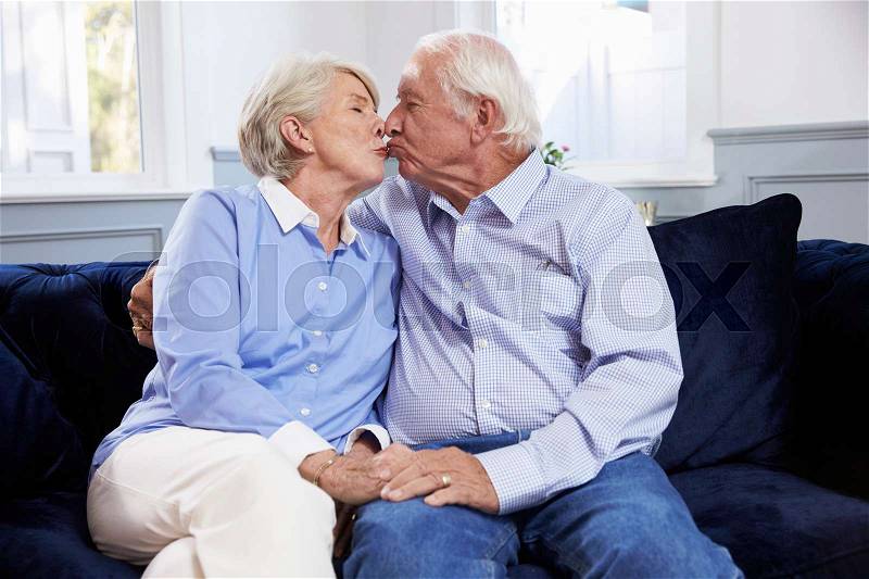 Affectionate Senior Couple Sitting On Sofa At Home, stock photo