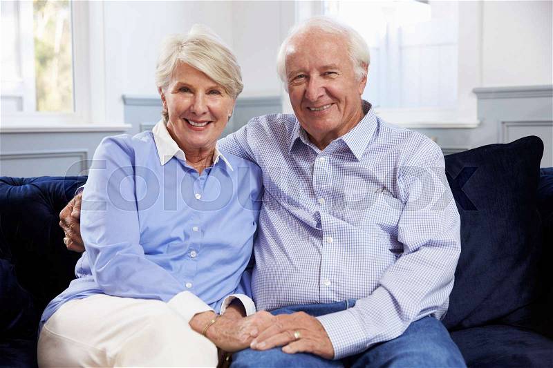 Portrait Of Senior Couple Sitting On Sofa At Home, stock photo