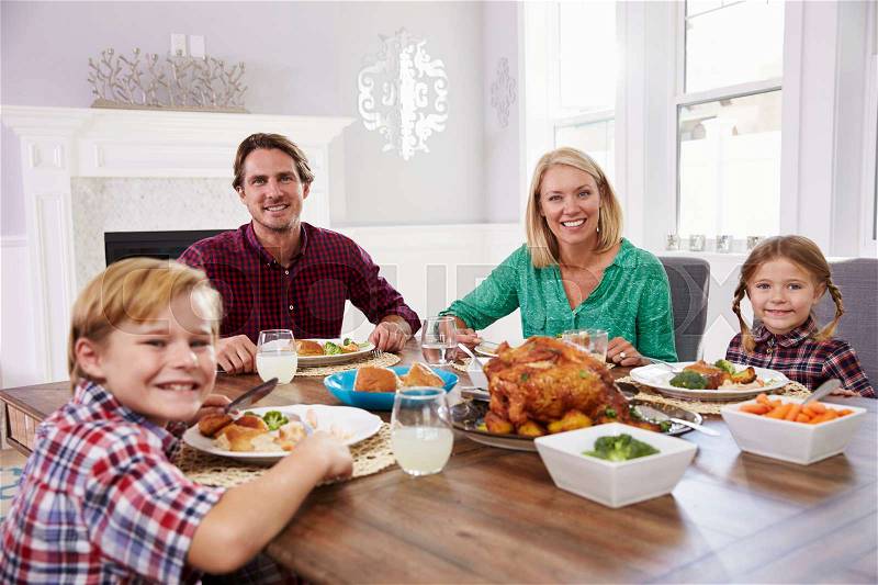 Portrait Of Family Sitting Around Table Eating Meal At Home, stock photo