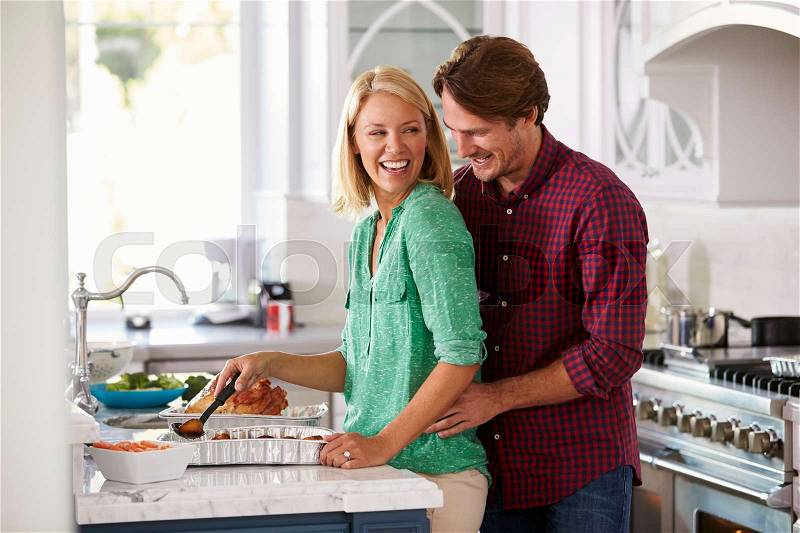 Couple Make Roast Turkey Meal In Kitchen Together, stock photo