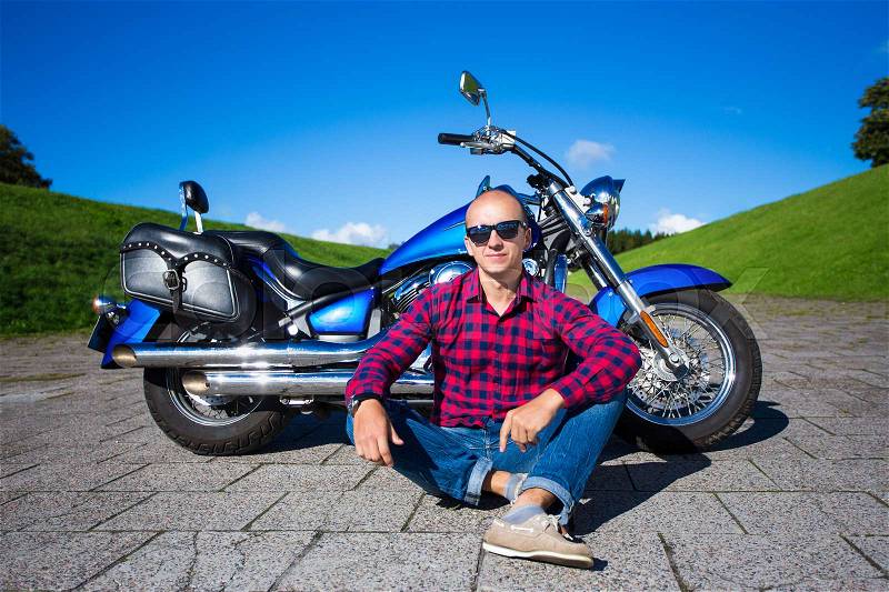 Young handsome man and blue retro motorcycle, stock photo