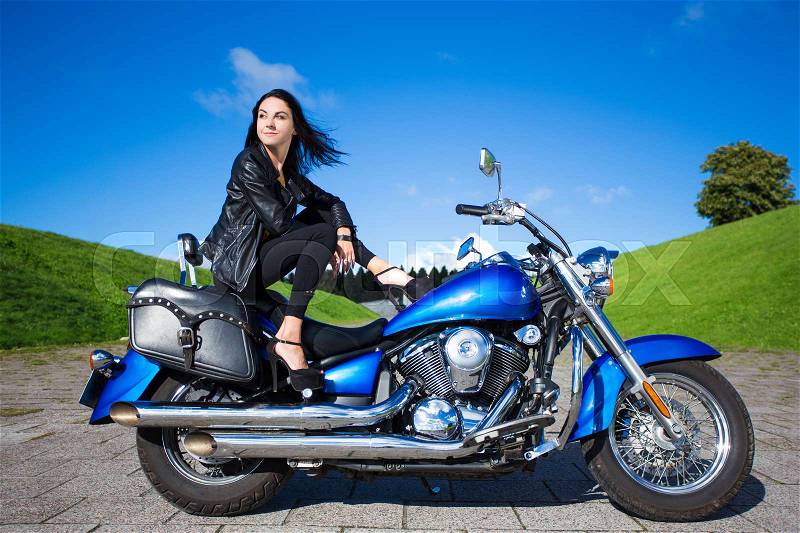 Young sexy woman posing with blue vintage motorbike, stock photo