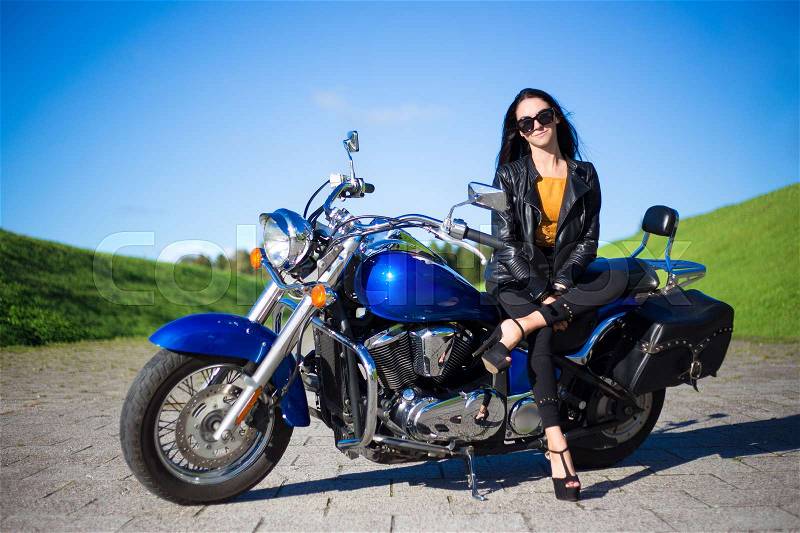 Young beautiful woman sitting on beautiful retro motorcycle, stock photo