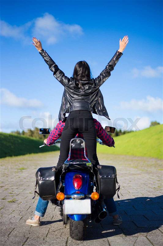Back view of happy young couple going to travel on motorbike, stock photo