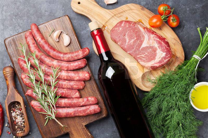 Sausages, meat, red wine and ingredients for cooking. Top view on stone table, stock photo