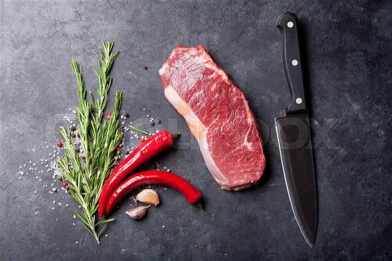 Raw striploin steak with rosemary, salt and pepper cooking over stone table. Top view, stock photo