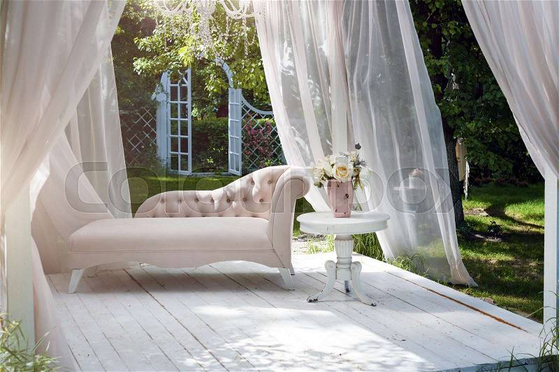Summer garden gazebo with curtains and sofa for relaxation, stock photo