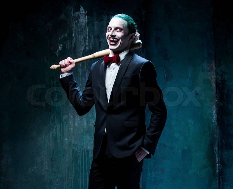 Bloody Halloween theme: The crazy joker face on black background with baseball bat, stock photo