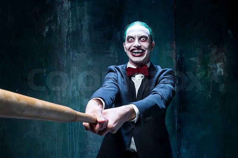 Bloody Halloween theme: The crazy joker face on black background with baseball bat, stock photo