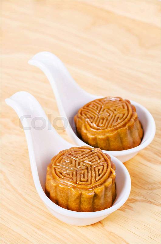 Two moon cake in white spoon on wooden background, stock photo