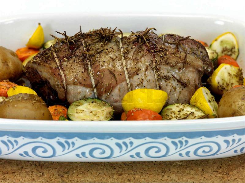A lamb roast with vegetables in a baking tray, stock photo