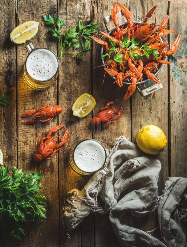 Two pints of wheat beer and boiled crayfish with lemon and parsley over old wooden rustic background, top view, stock photo