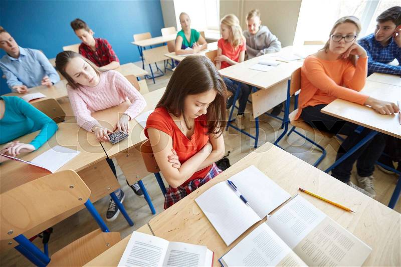 Education, bullying, conflict, problem and people concept - students gossiping behind classmate back at school, stock photo
