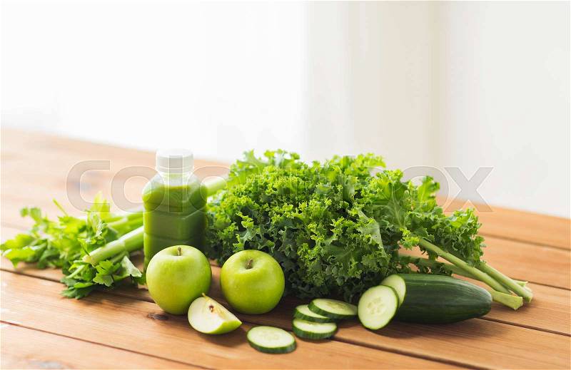 Healthy eating, food, dieting and vegetarian concept - bottle with green juice, fruits and vegetables on wooden table, stock photo