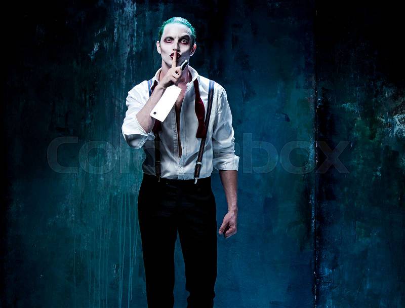 Bloody Halloween theme: The crazy joker face on black background with knife, stock photo