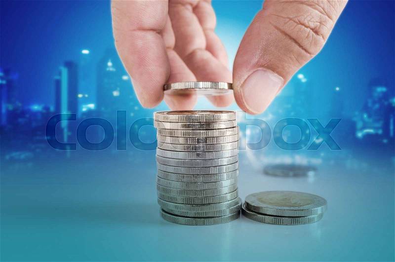 Saving money concept. hand putting coin to stacks of coins with city scape background, stock photo