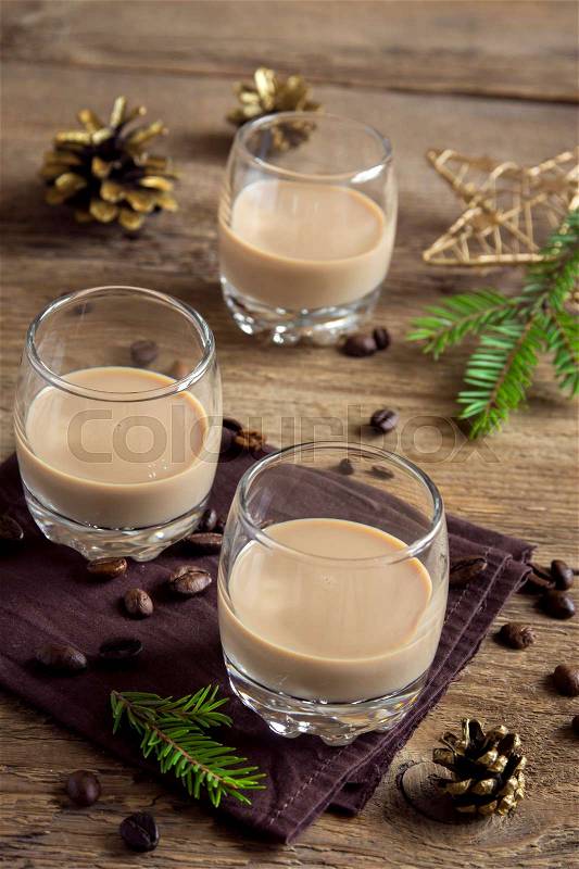 Irish cream coffee liqueur with Christmas decoration and ornaments over rustic wooden background - festive Christmas alcoholic drink, stock photo