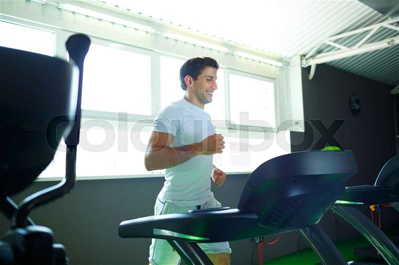 Athletic man doing cardio training program in fitness center, stock photo