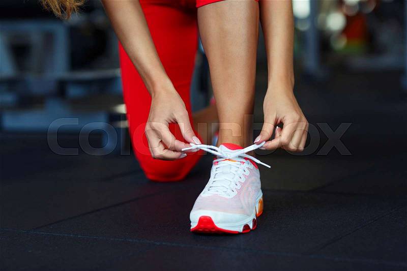 Running shoes - woman tying shoe laces. Closeup of fitness woman getting ready for engage in the gym, stock photo