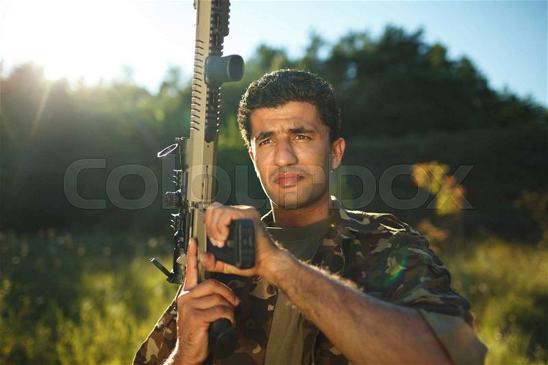 Man of Arab nationality in camouflage with a shotgun in an outdoor, stock photo