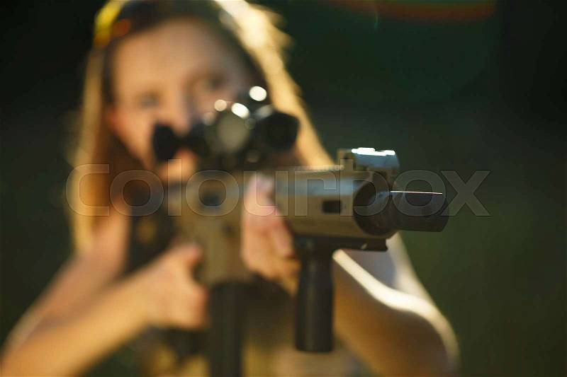 A young girl with a gun for trap shooting aiming at a target. Short depth of field, focus on the barrel, stock photo