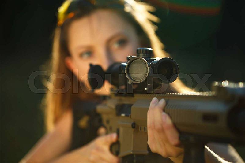 A young girl with a gun for trap shooting aiming at a target, stock photo
