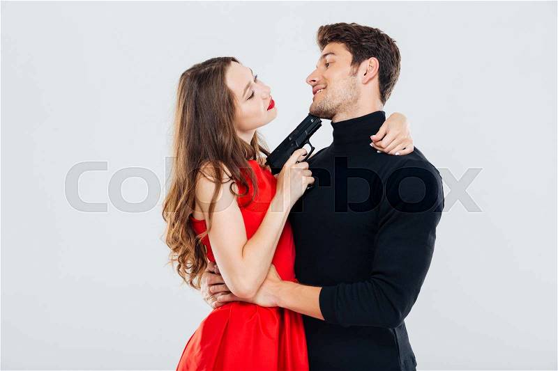 Happy young couple embracing and posing with gun, stock photo
