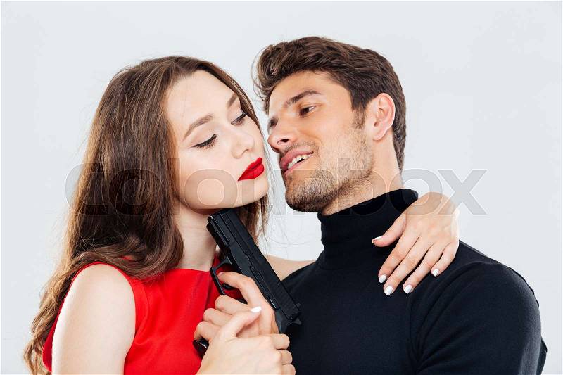 Sensual young couple hugging and posing with gun, stock photo