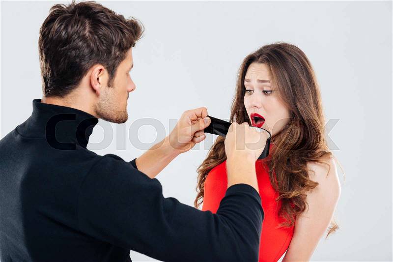Criminal man covering mouth of scared woman with black tape, stock photo
