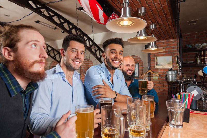 Man Group In Bar Hold Glasses Happy Smiling, Drinking Beer, Mix Race Cheerful Friends Meeting Pub Communicate Talking, stock photo