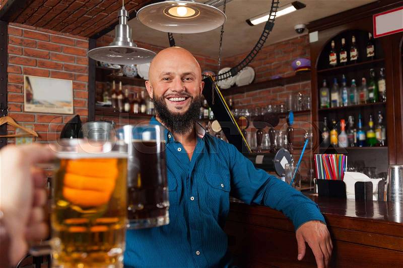 Bearded Man In Bar Clink Glasses Toasting, Drinking Beer Hold Mugs, Cheerful Friends Meeting Pub Communicate Talking, stock photo